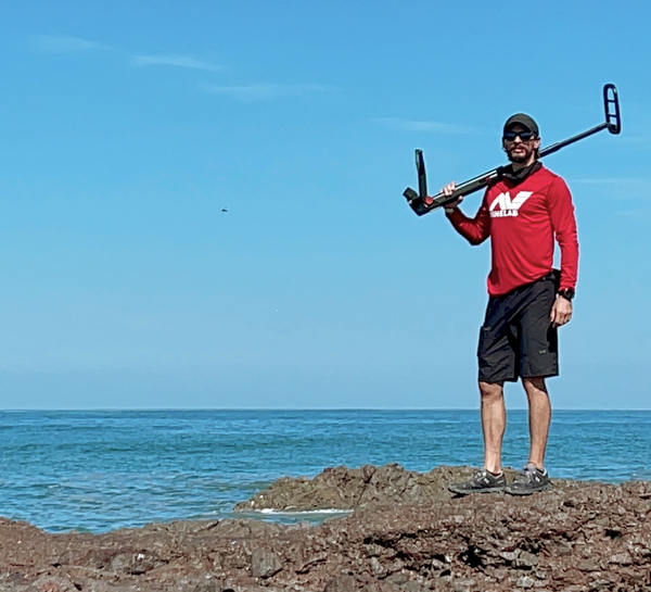 Hombre con un detector de metales en el hombro en una playa