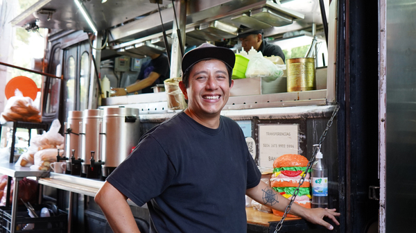 Hombre de pie de frente a un foodtruck posa para la foto