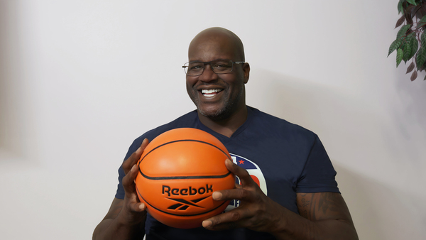 Shaq sosteniendo un balón Reebook entre las manos mientras mira a la cámara de frente