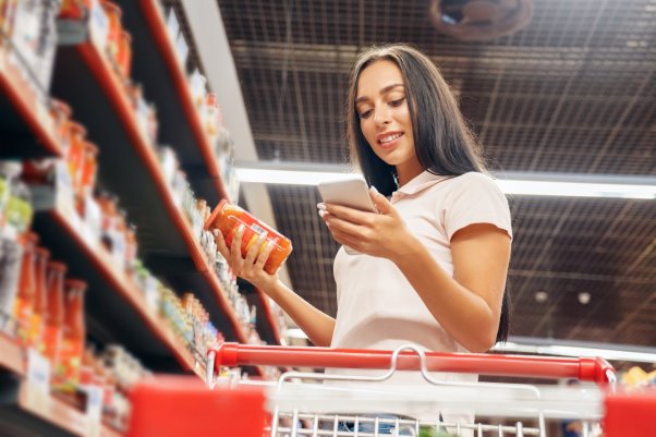 Mujer comprando a través de su teléfono móvil mientras sostiene su tarjeta de crédito en la otra mano