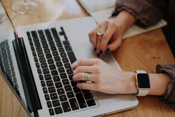 Manos femeninas trabajando, sobre un escritorio de madera, con una PC