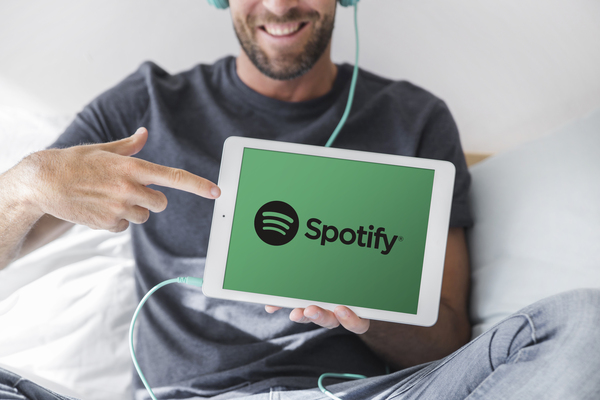 Hombre joven sosteniendo una tablet con el logo de spotify en la pantalla