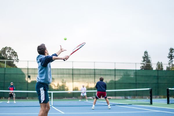 Hombres jóvenes jugando poadel al aire libre