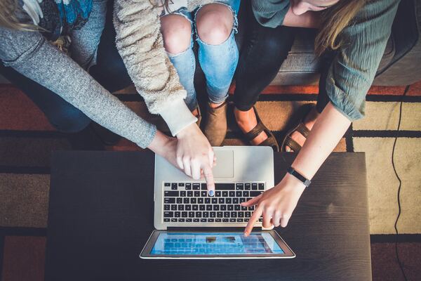 Jóvenes señalando la pantalla de una laptop con la intención de comprar