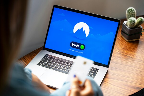 Hombre con una tarjeta de crédito en la mano y un VPN en la pantalla de la PC