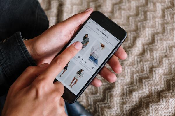 Mano masculina sosteniendo un smartphone mientras observa un en un marketplace