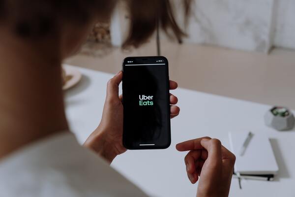 Una mujer con el smartphone en la mano entrando en la app de Uber Eats