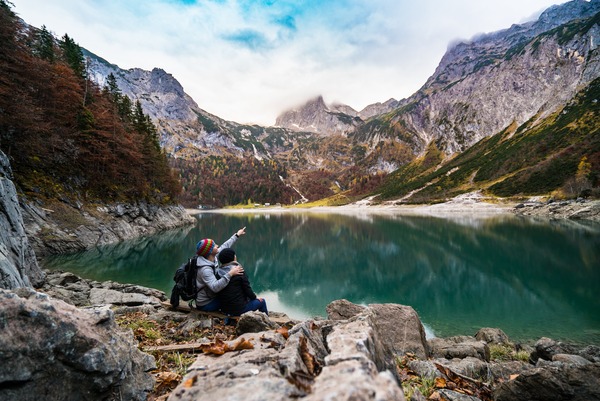 Pareja de viajeros mirando las montañas desde un valle