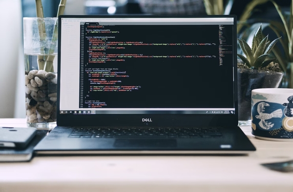 Computadora Dell sobre un escritorio con código de programación en la pantalla
