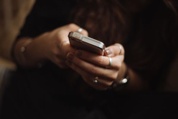 Mujer sosteniendo su celular y, al parecer, manteniendo una conversación vía chat