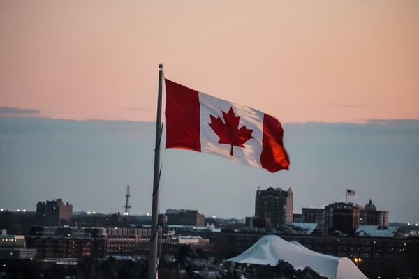 Bandera canadiense ondeando con la ciudad de fondo