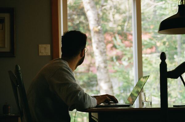 Hombre mirando la ventana desde el escritorio de su habitación